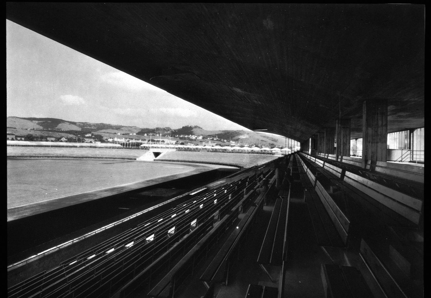 View of covered seating area of large stadium, showing rows of nearly empty seats, Germany