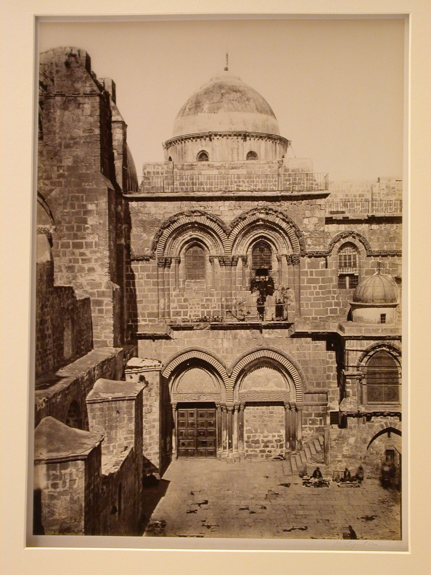 Church of the Holy Sepulchre, view of entrance façade including uppermost part of entrance, dome over the rotunda, with figures standing on second-story window ledge, Jerusalem, Palestine