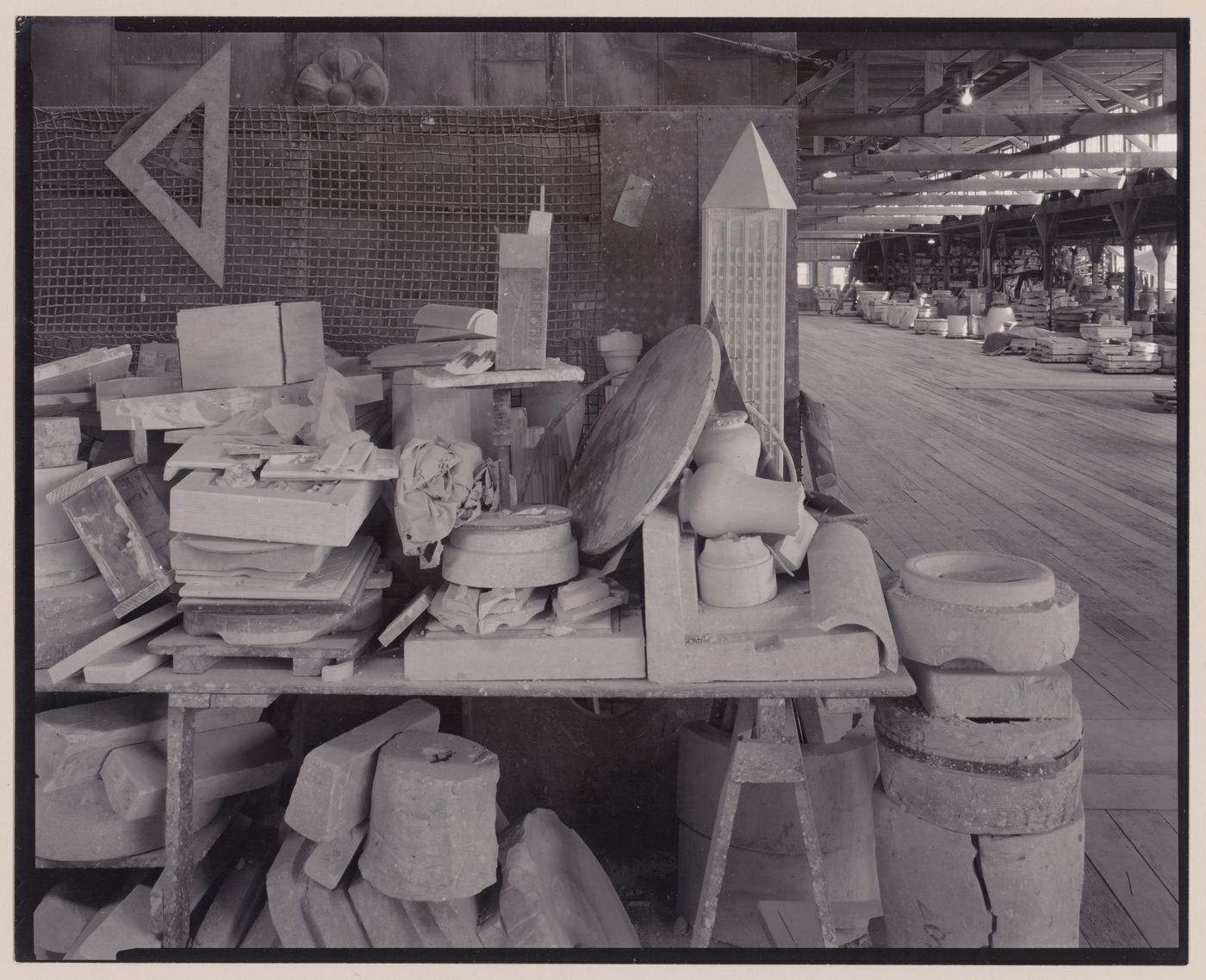 Gladding, McBean, terra-cotta factory, close-up of table stacked with terra-cotta molds in a large storage room.