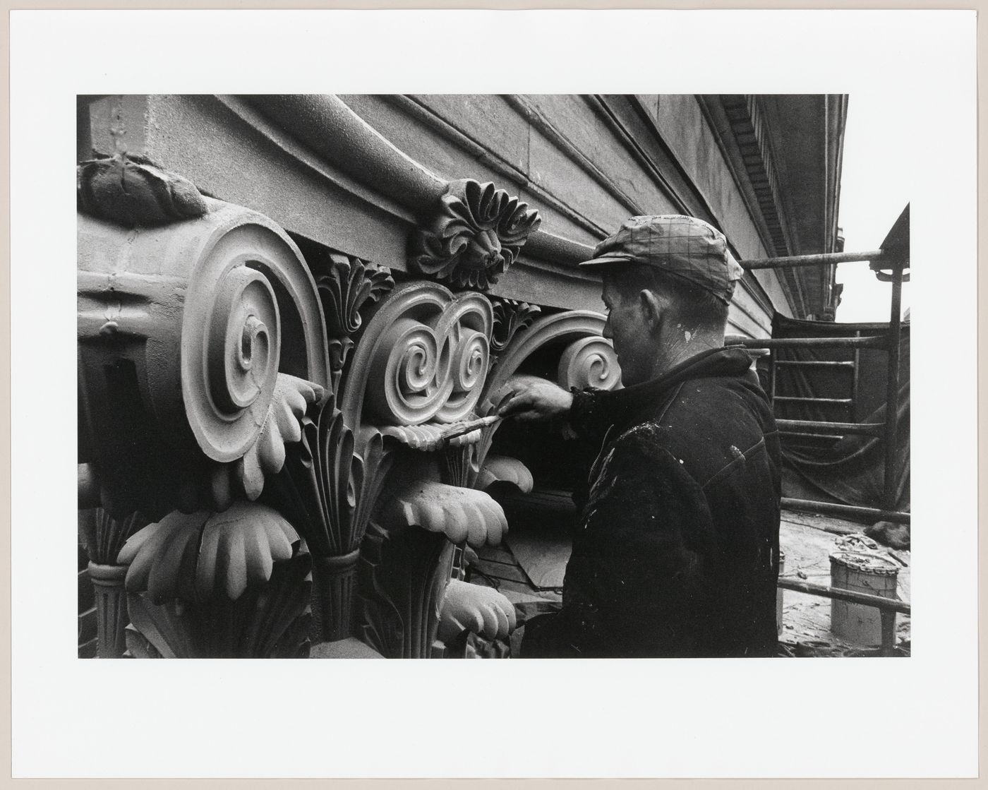 View of a worker brushing hypalon material onto the aluminium capital during the restoration of the Corinthian capitals of the principal façade of the Head Office of the Bank of Montréal, 119 rue Saint-Jacques, Montréal, Québec