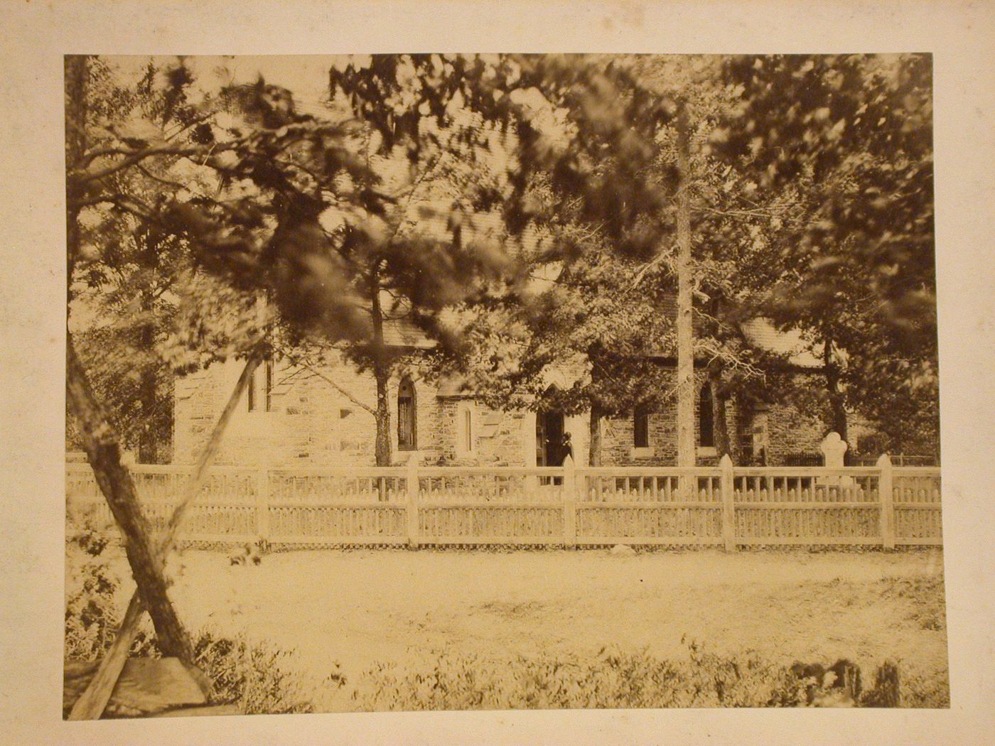 Out of focus view, obscured by trees, of a man entering a church, United States