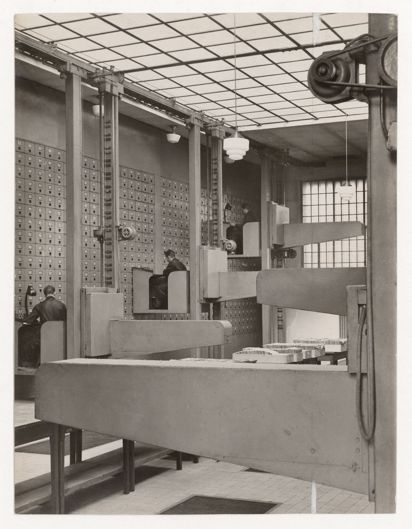 Interior view of the Central Social Insurance Institution showing men working in mobile work stations used to access the card catalog drawers, Prague, Czechoslovakia (now Czech Republic)