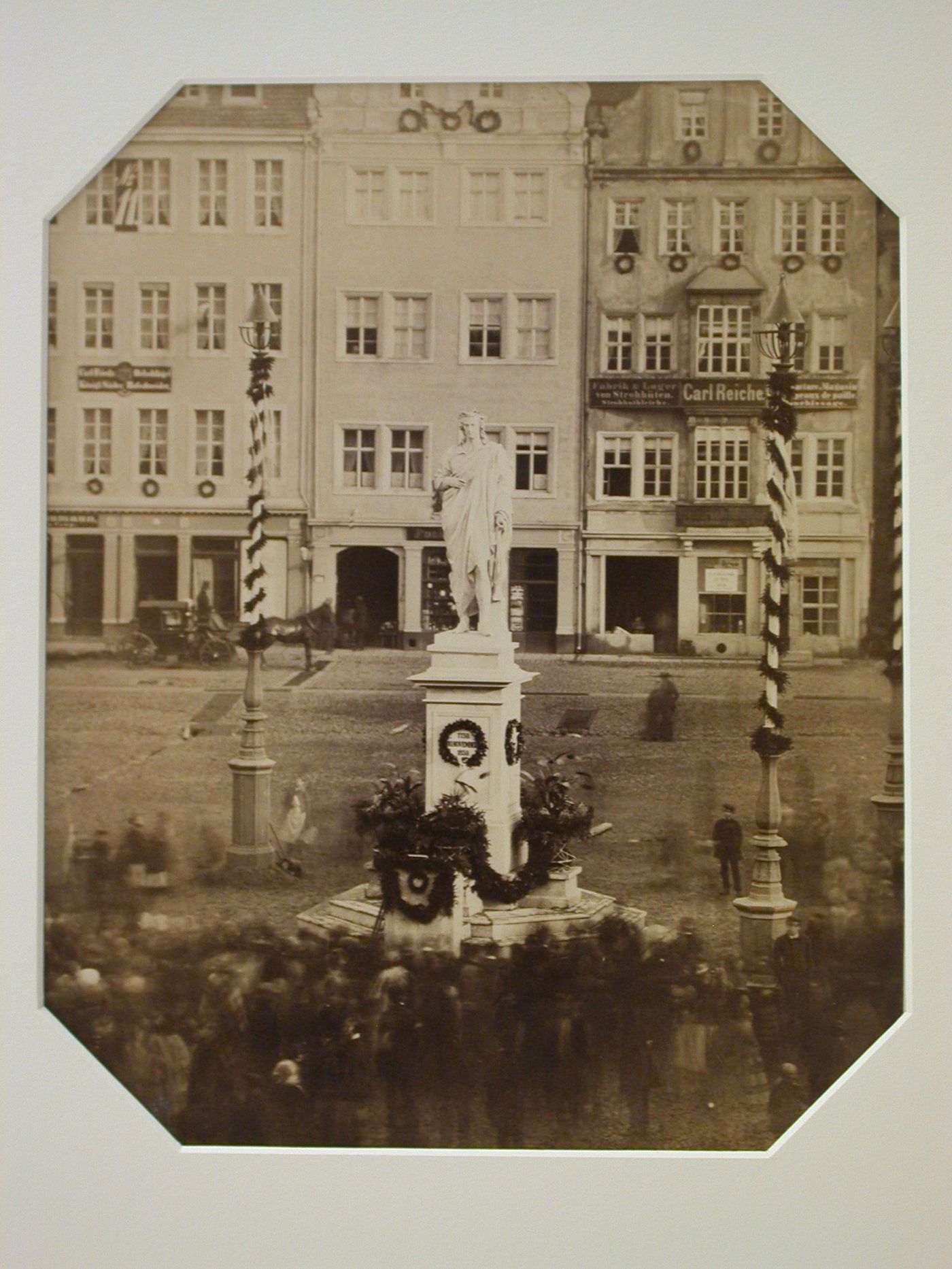 View of commemorative statue with wreaths, in square, surrounded by people, Dresden, Germany