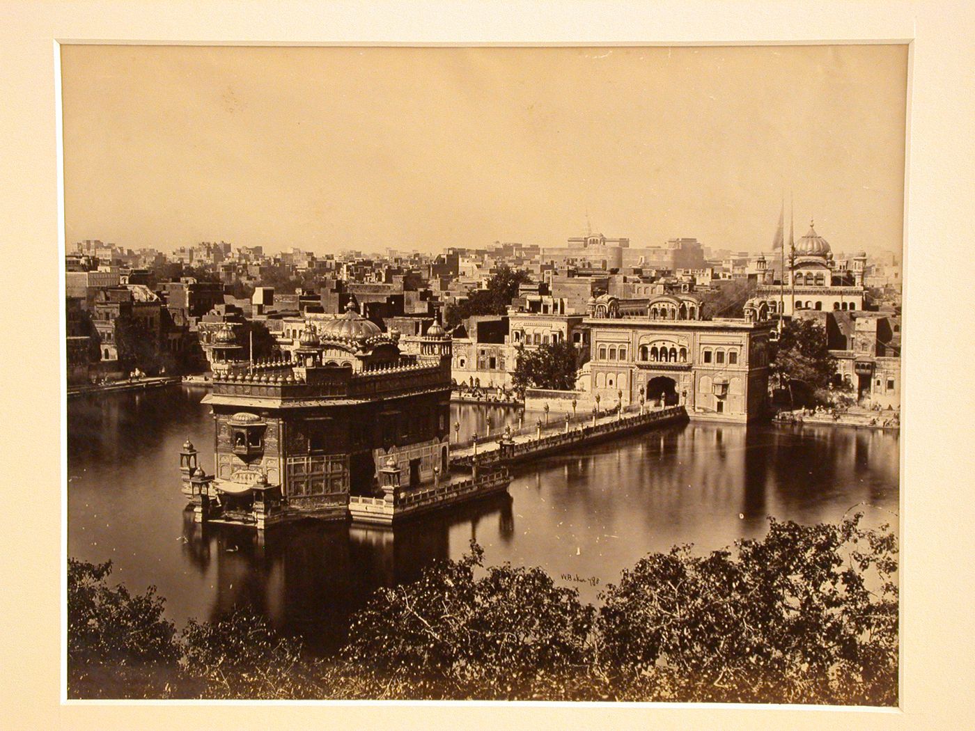 View of the Golden Temple (also known as the Harmandir) showing the pool (also known as the Amrit Sarowar or Pool of Nectar), causeway and entrance pavilion with the Akhal Takht and city in the background, Darbar Sahib temple complex, Amritsar, India