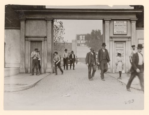View of workers, including a boy, exiting grounds of Singer Manufacturing Co. at lunch hour, and a girl carrying lunch, South Bend, Indiana, United States