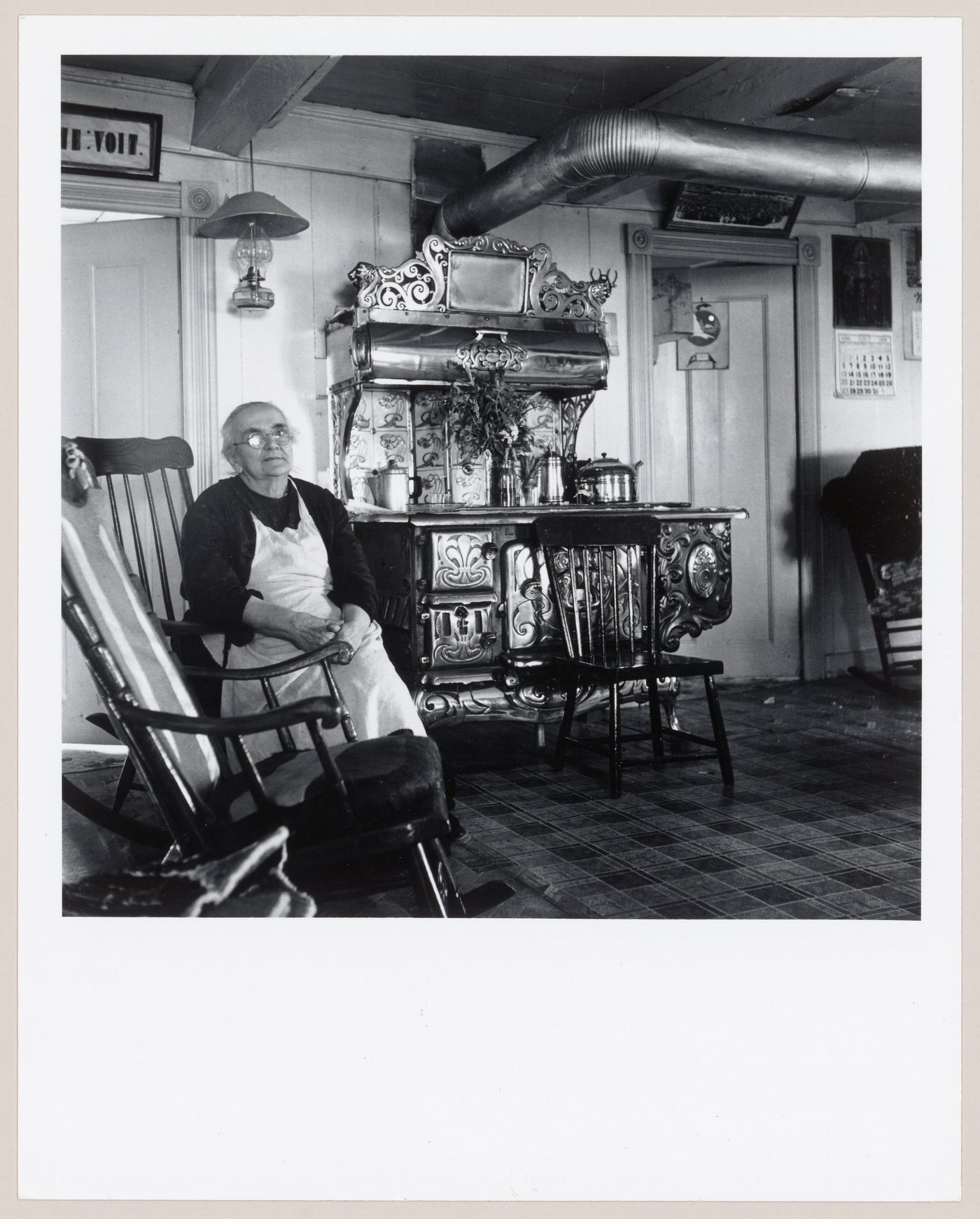 La conteuse Marie Demeules assise près du poêle à bois dans sa cuisine, L'Isle-aux-Coudres, Charlevoix, Québec