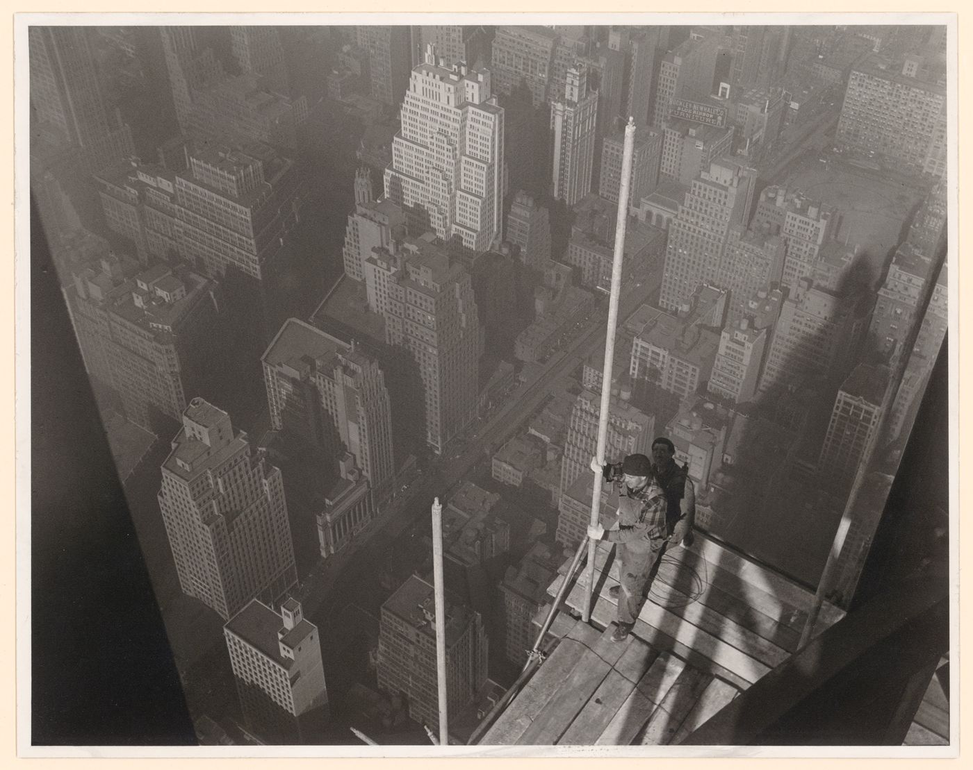 Workers standing on Empire State Building scaffold, overlooking New York City, New York