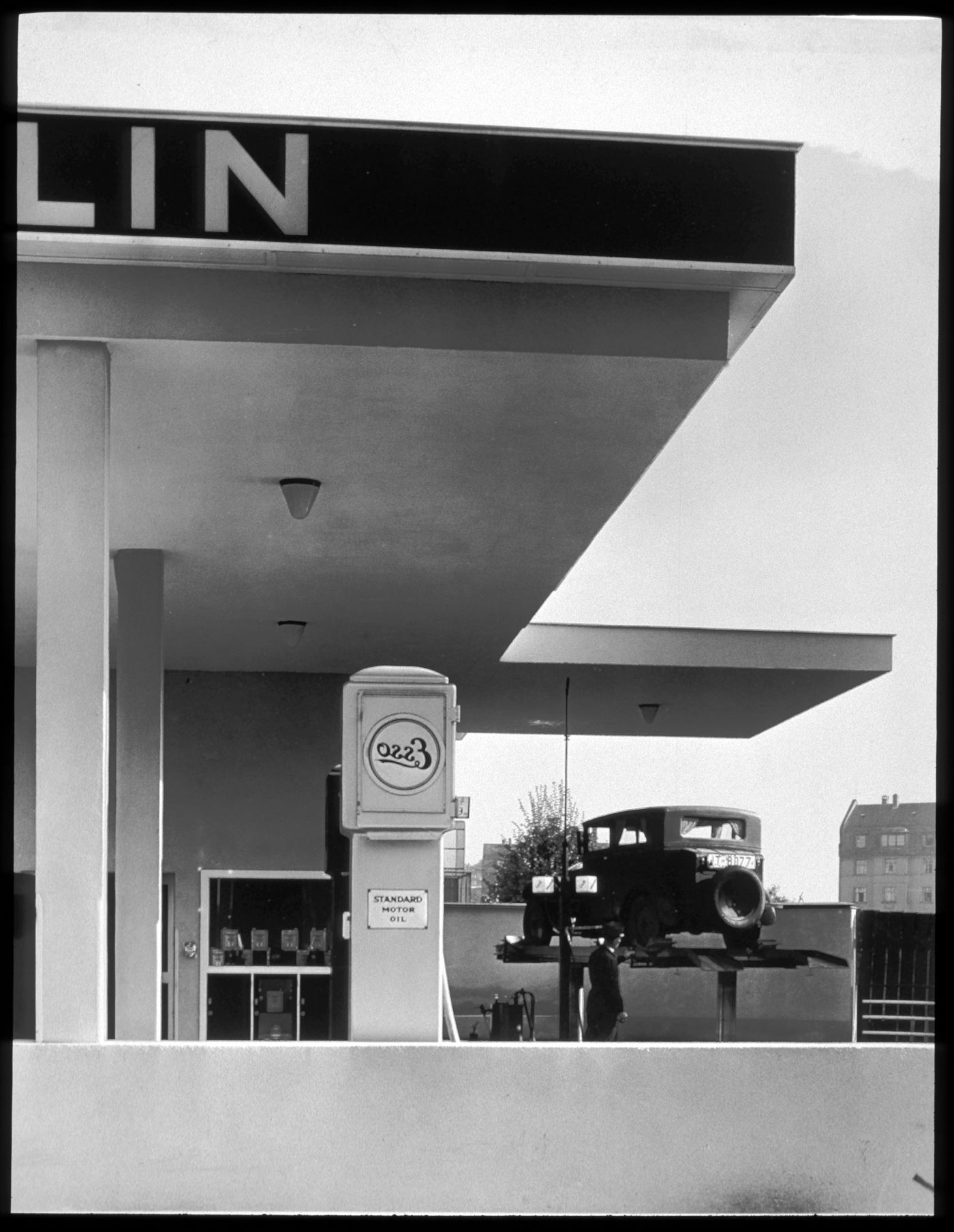 Dapolin auto service station, partial view showing "Esso" pump, man by car on a lift, Frankfurt am Main, Germany