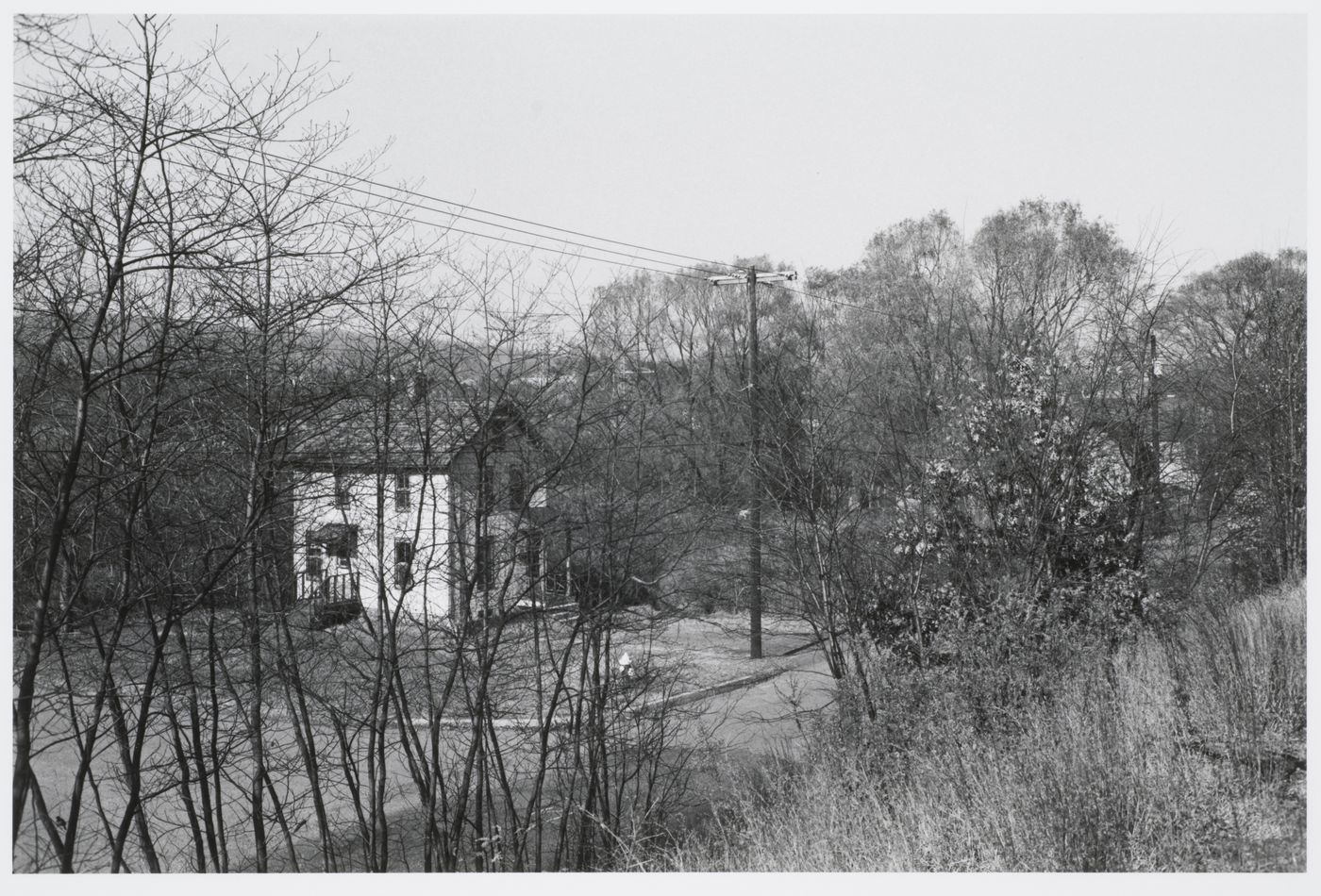 Two-storey house seen from hill across street; includes trees, electricity wires, fire hydrant, Suffern, New York