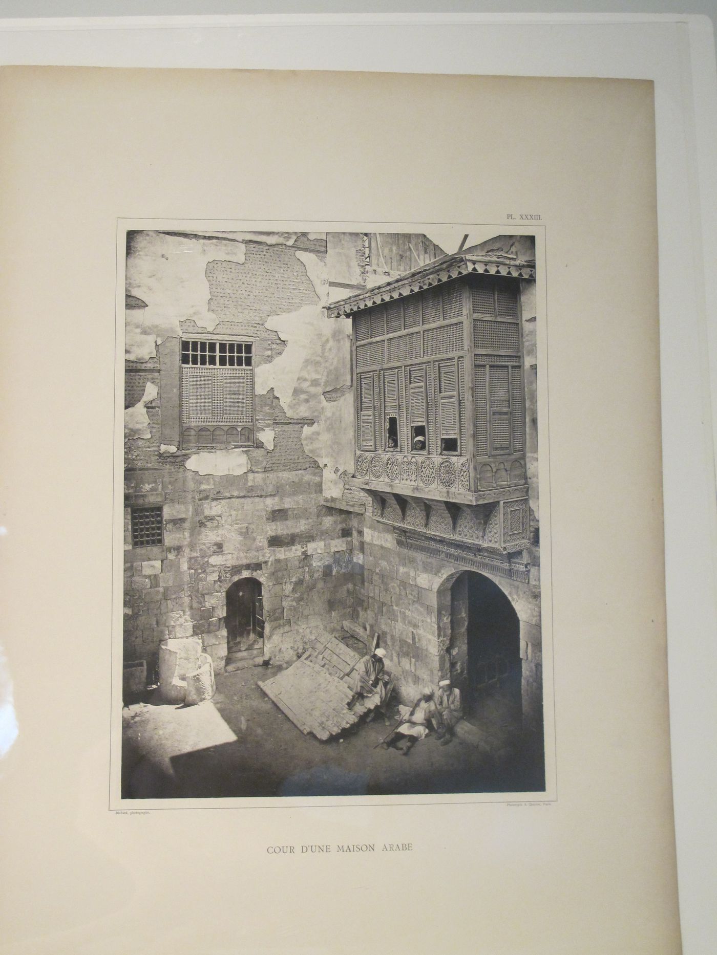 View of inner courtyard of residential building with two children looking through a mashrabiya and three men resting below, Cairo, Egypt