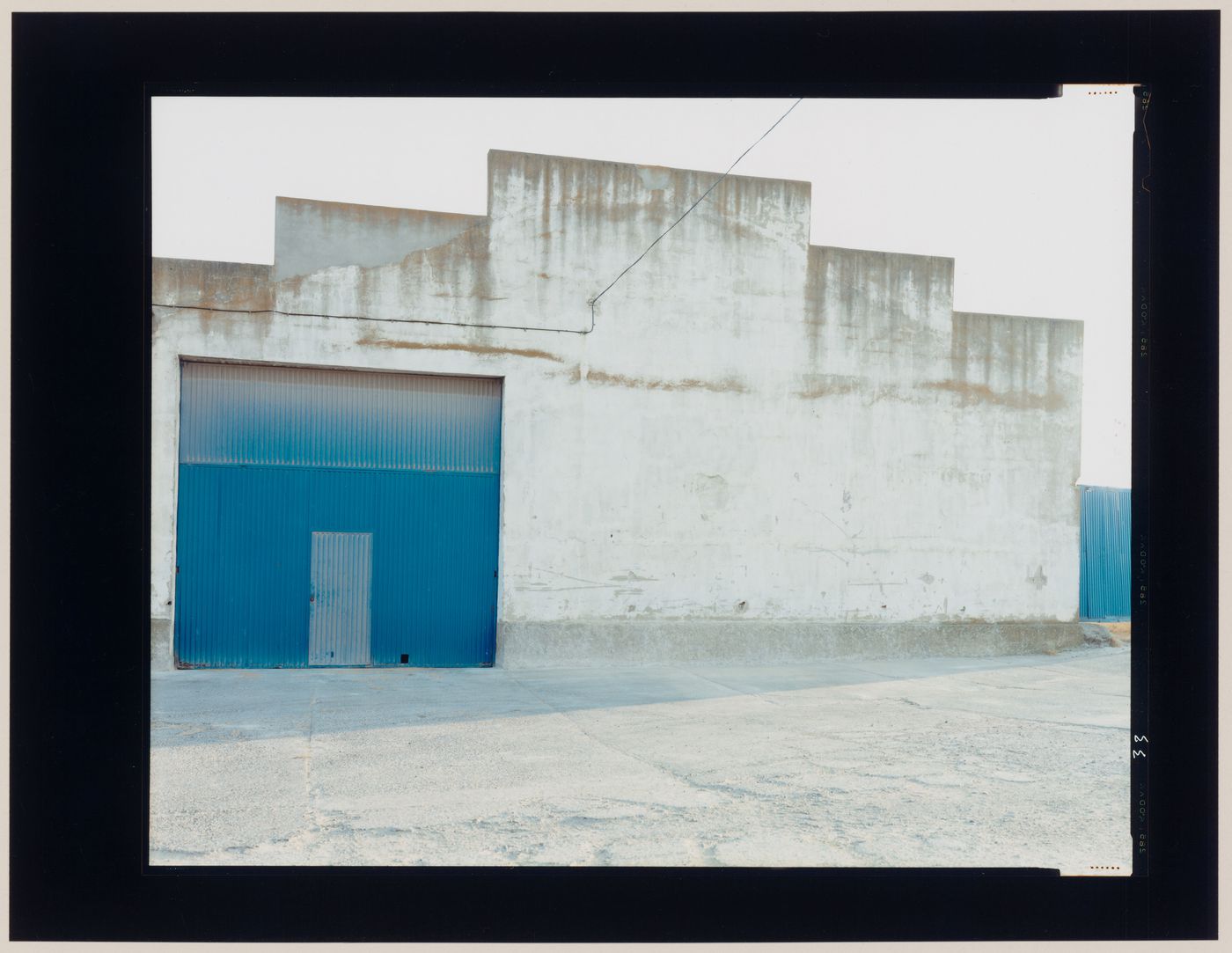 View of an agricultural building showing a concrete wall and a metal door, Castrojeriz, Burgos Province, Spain (from the series "In between cities")