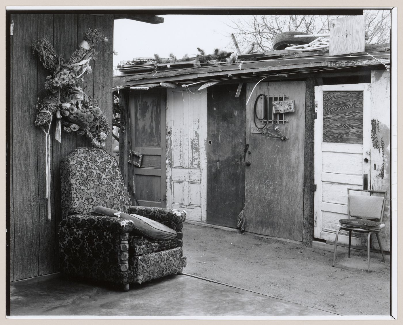 View of cross decorated with flowers hung above upholstered chair in outdoor space, Old Pascua, Tucson, Arizona, United States (from a series documenting the Yaqui community of Old Pascua)