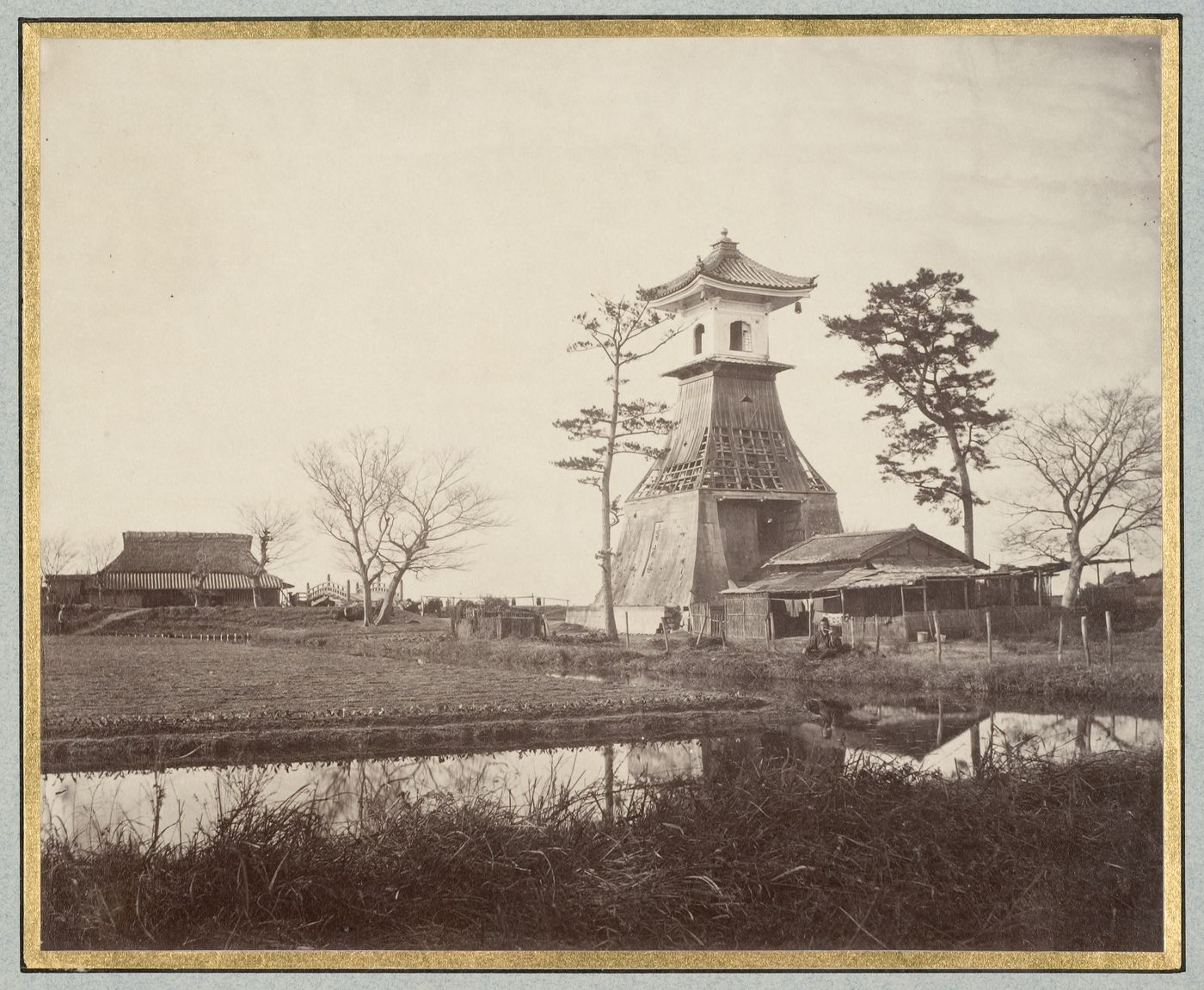View of a wooden tower and buildings showing a moat and a bridge, near Kobe [?], Japan