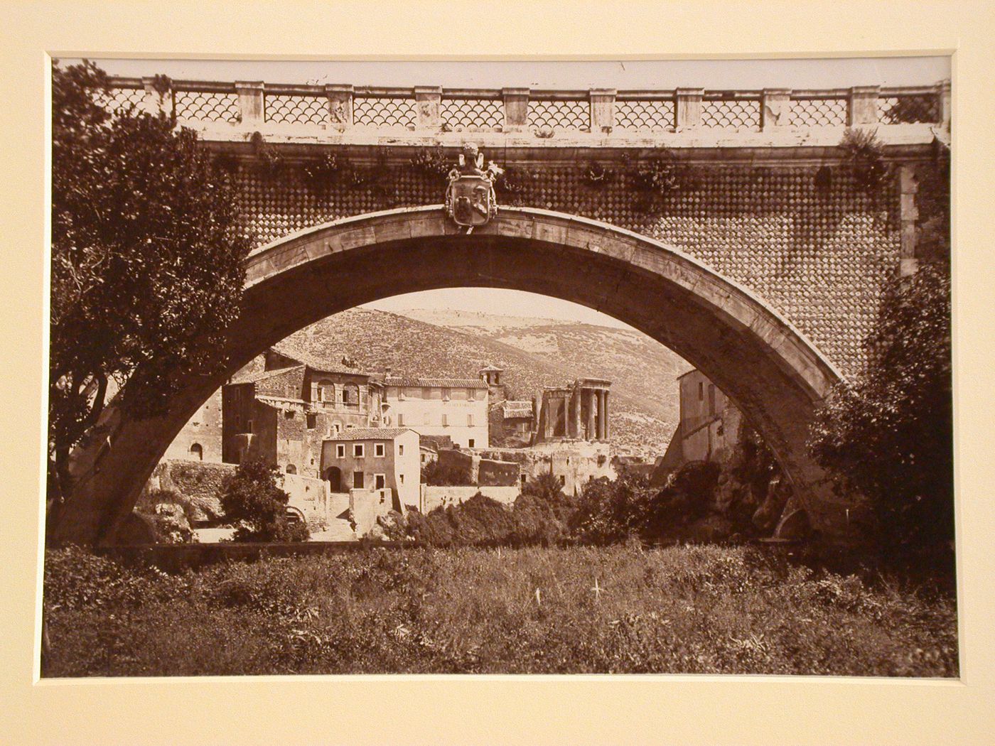 View of town and surrounding hills through arch of bridge, Tivoli, Italy