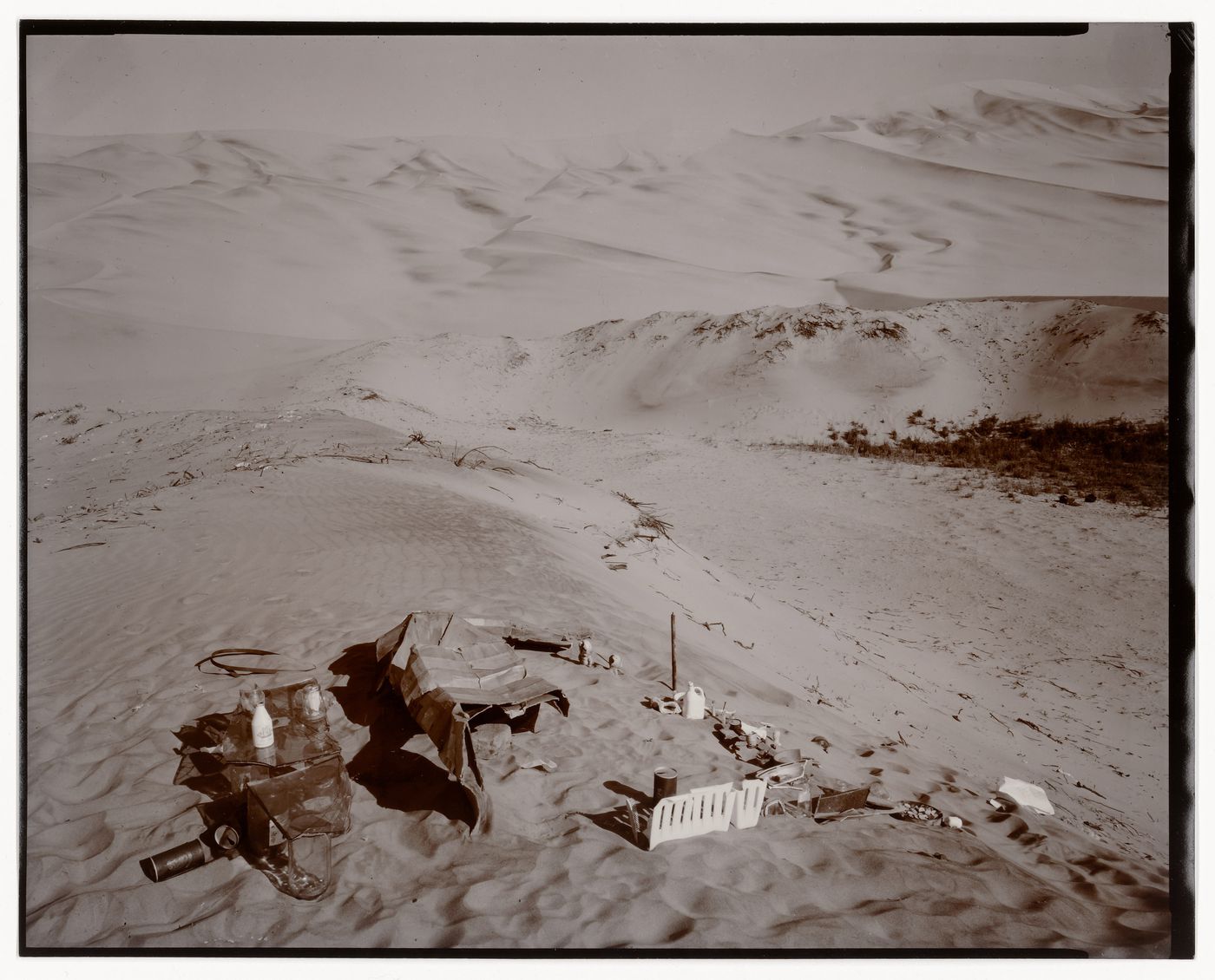 View of an arrangement of objects and refuse on sand with dunes in the background, Ica, Peru