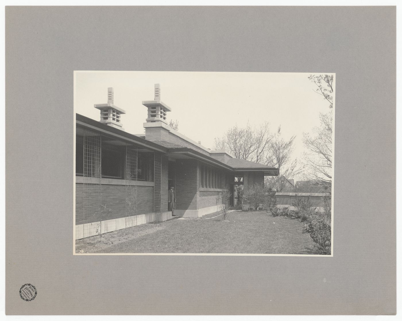 View of Darwin D. Martin House showing a man standing in the doorway and a raking view of the pergola and conservatory, Buffalo, New York