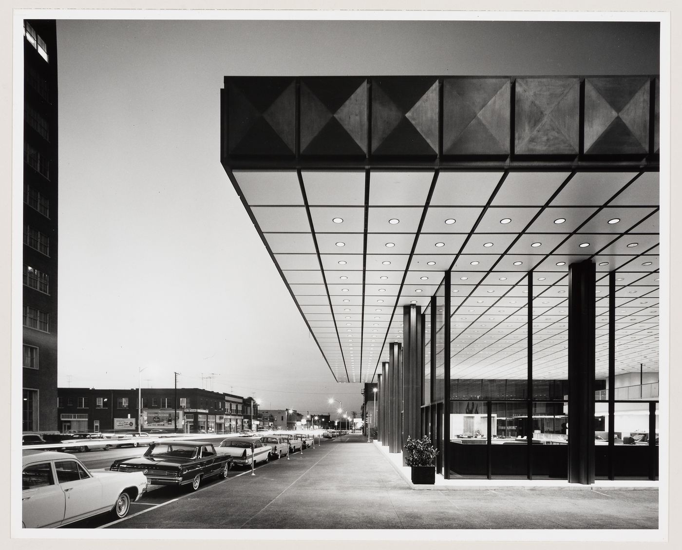 Oblique view of the entrance to the Phillips Petroleum Building showing low-rise buildings, a street and parked automobiles, Bartlesville, Oklahoma