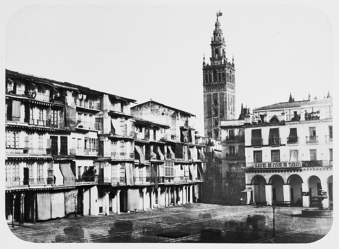 The large square, apartment houses, shops, with tower of Giralda [?] in background, Seville, Spain