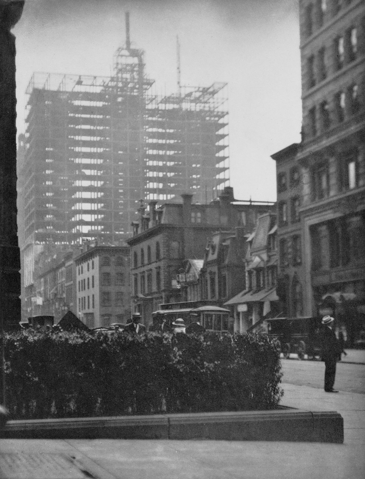 View of man on street with older buildings, new skyscraper under construction behind, New York City, New York