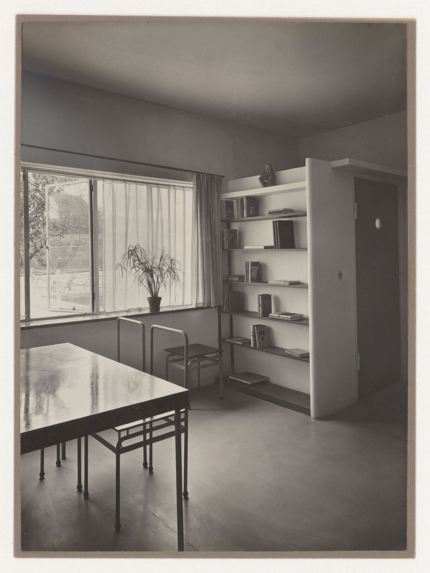 Interior view of the living room of House 8 showing a table, chairs and built-in bookshelf, Weissenhofsiedlung, Stuttgart, Germany