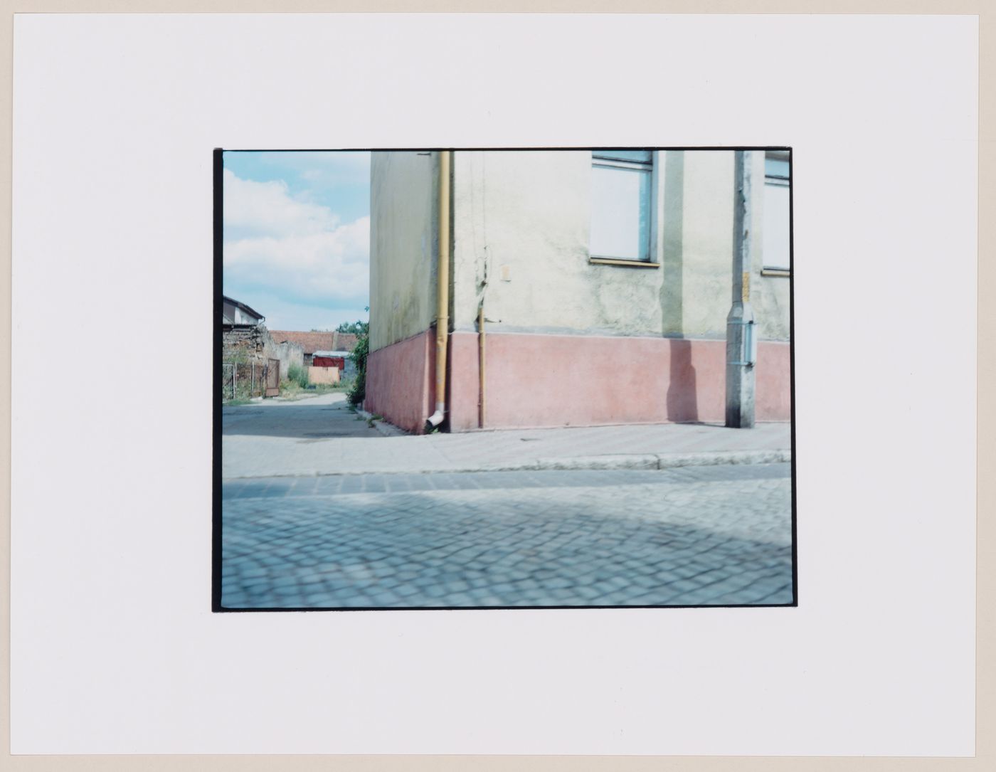 View of the corner of a building and an alley showing a cobbled street in the foreground, Braniewo, Poland (from the series "In between cities")