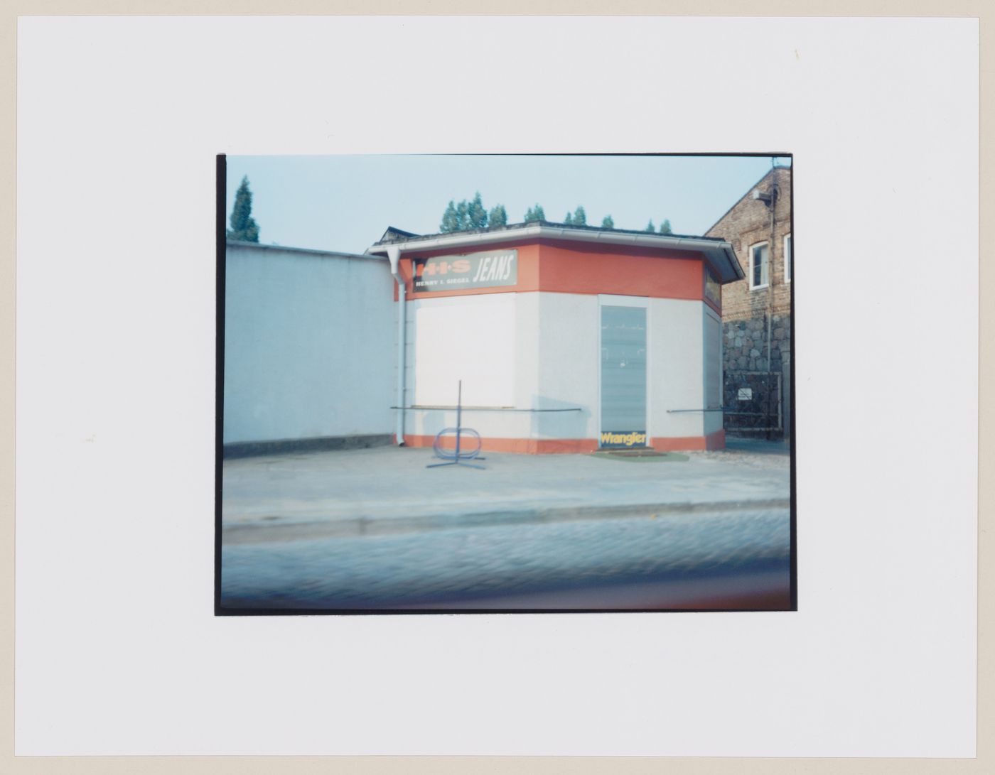 View of a jeans store with a shuttered door and window, Braniewo, Poland (from the series "In between cities")