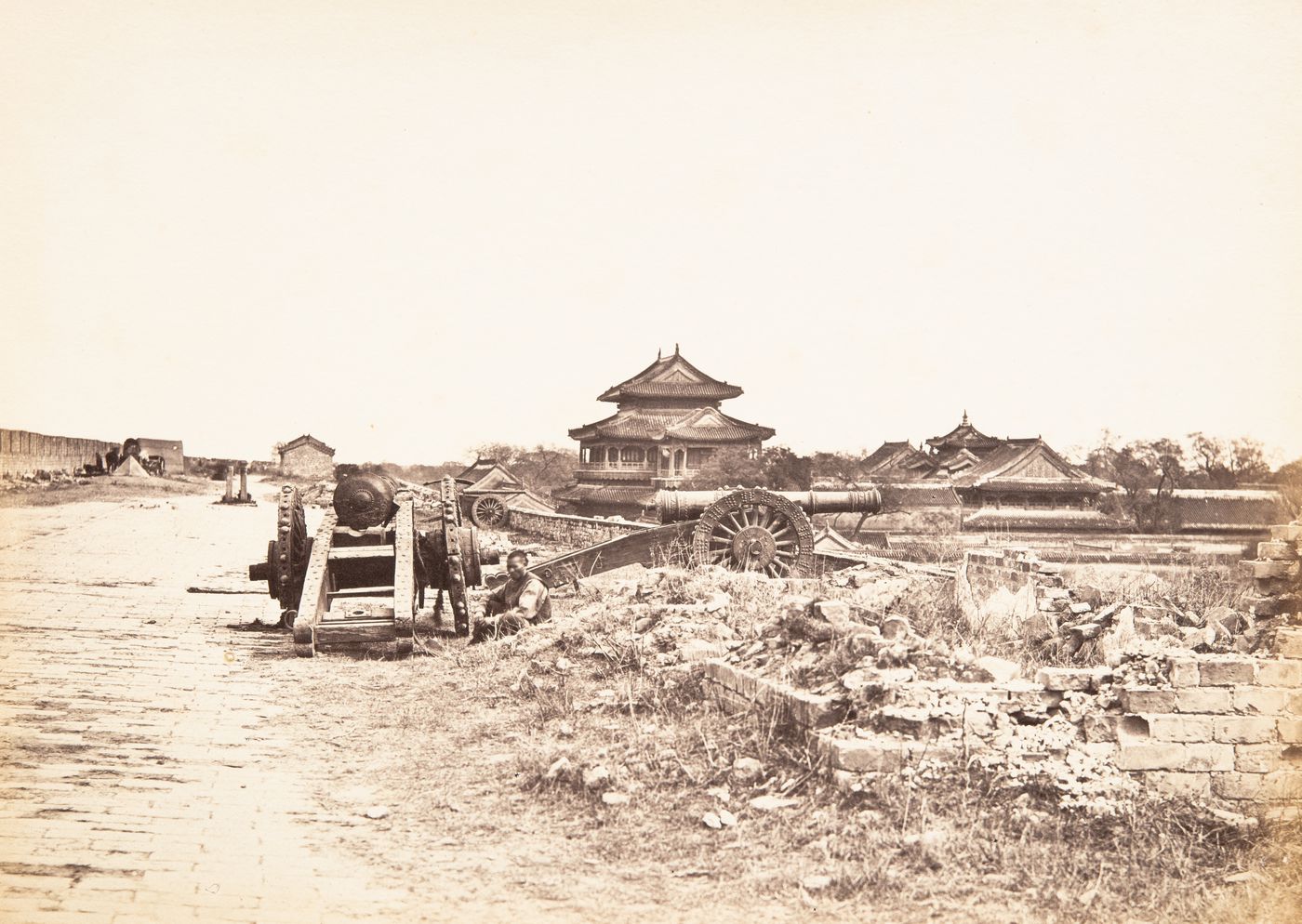 View of the top of the wall of the Inner City, showing cannons, with the Yonghe Gong [Lamasery of Harmony and Peace] (also known as the Lama Temple) in the background, Peking (now Beijing), China