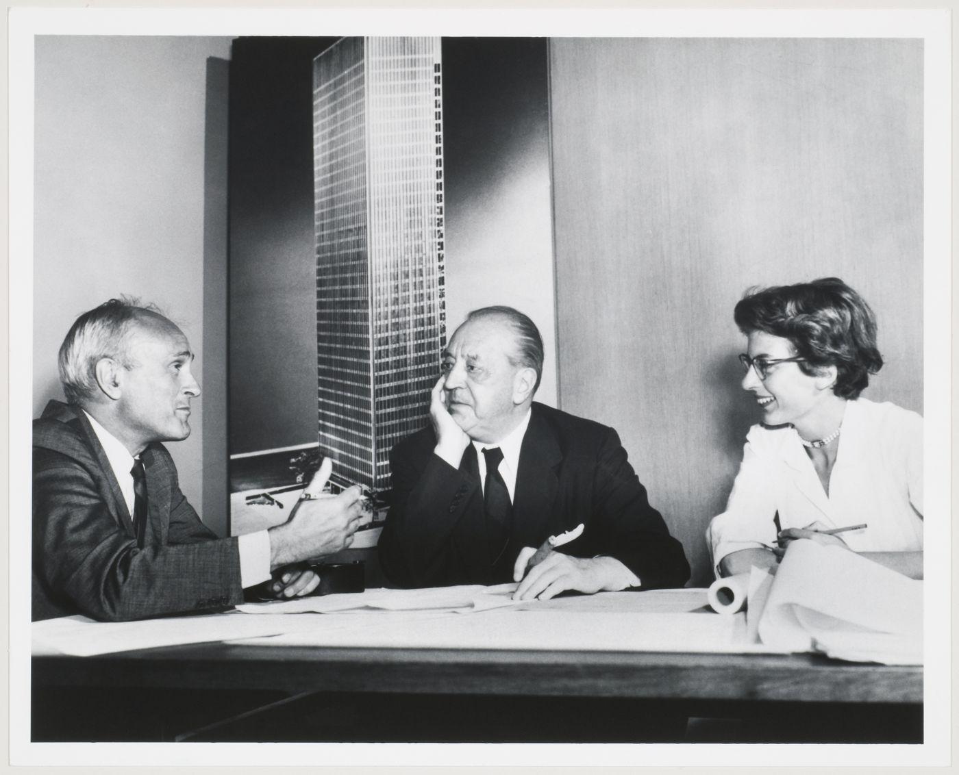 Philip Johnson, Mies van der Rohe and Phyllis Lambert in front of an image of the model for the Seagram Building, New York City (Ludwig Mies van der Rohe, Philip Johnson, architects; Kahn & Jacobs, associate architects, 1954-58)