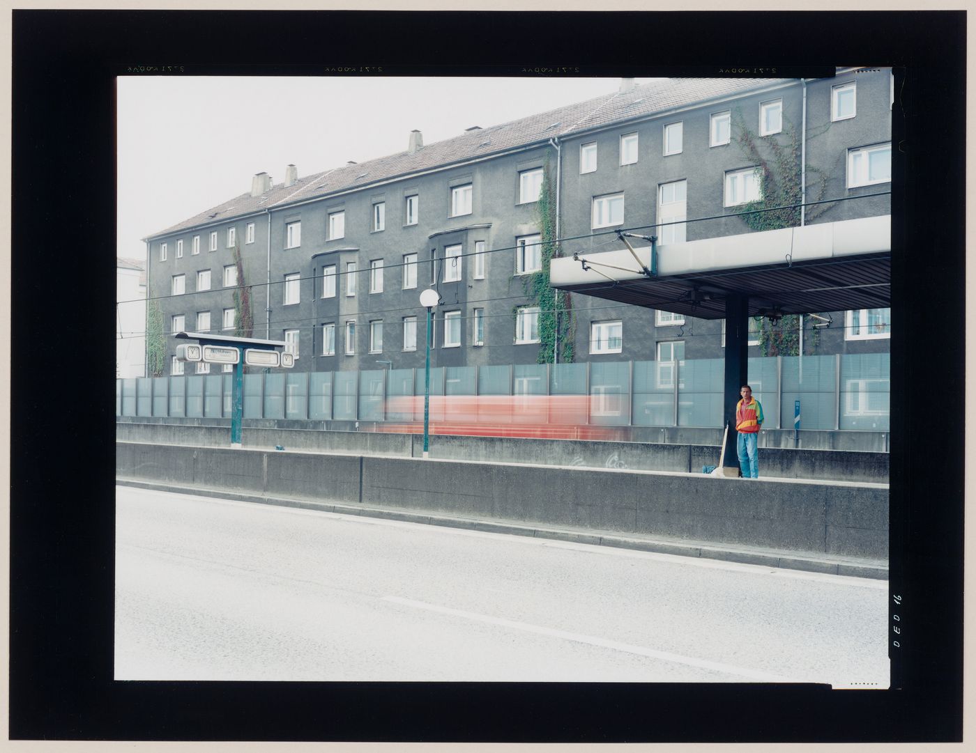 View of apartment houses, a road and a man on a train platform, Essen, Germany (from the series "In between cities")