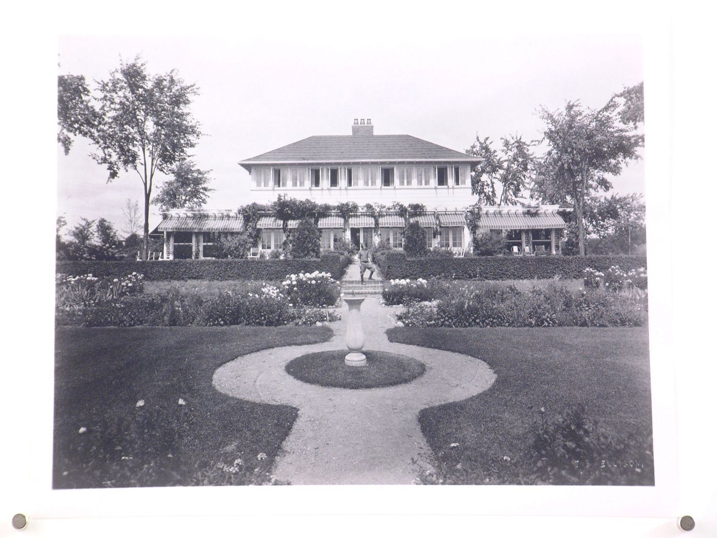 View of the rear façade of Albert Kahn's summer cottage from the garden showing a child on the stairs, Walnut Lake, Michigan