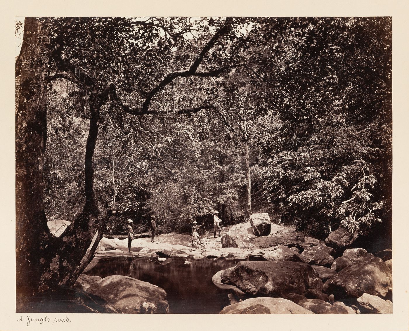 View of men walking along a riverbank, Ceylon (now Sri Lanka)