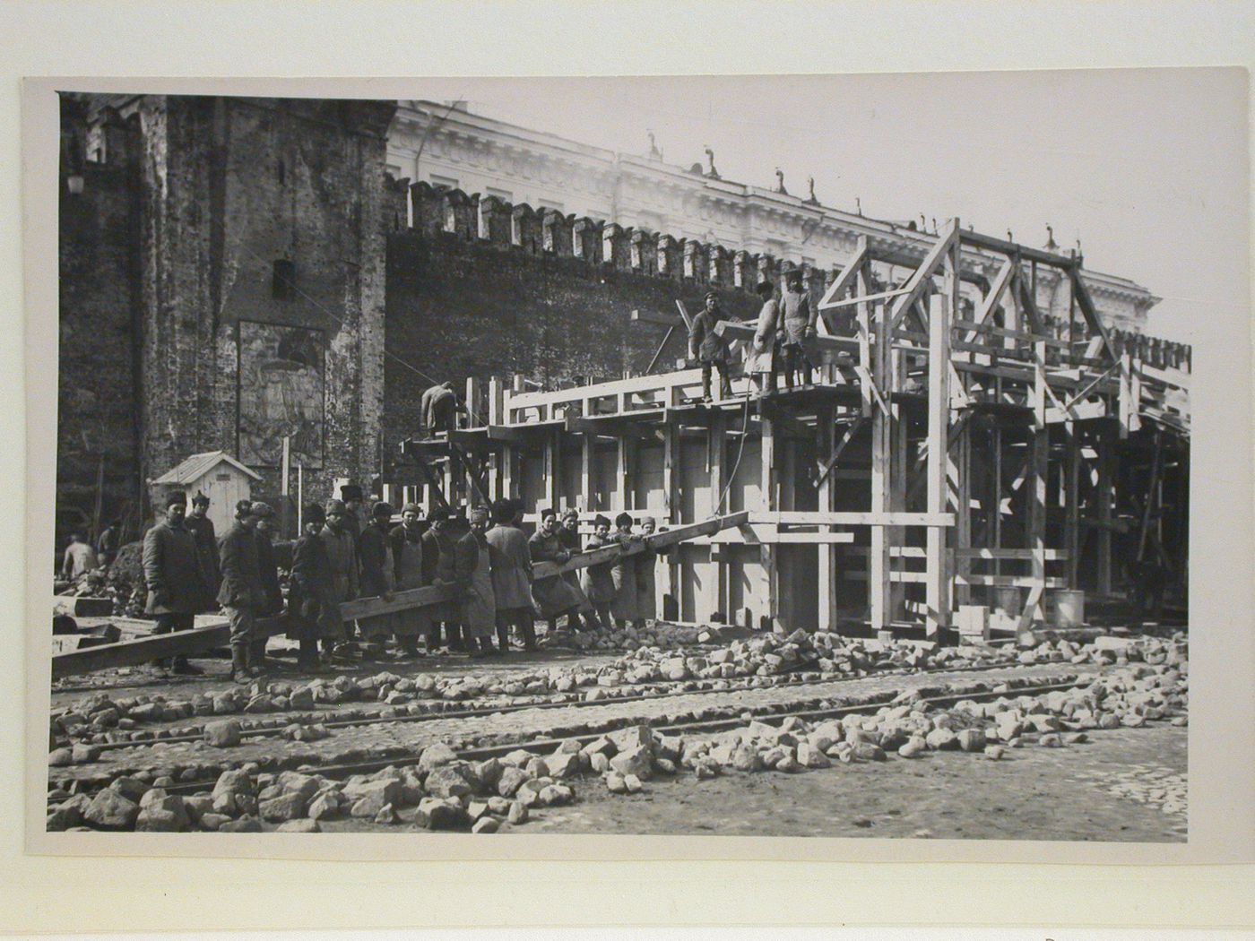 View of the second wooden Lenin Mausoleum under construction showing workers with a wooden beam, Red Square, Moscow