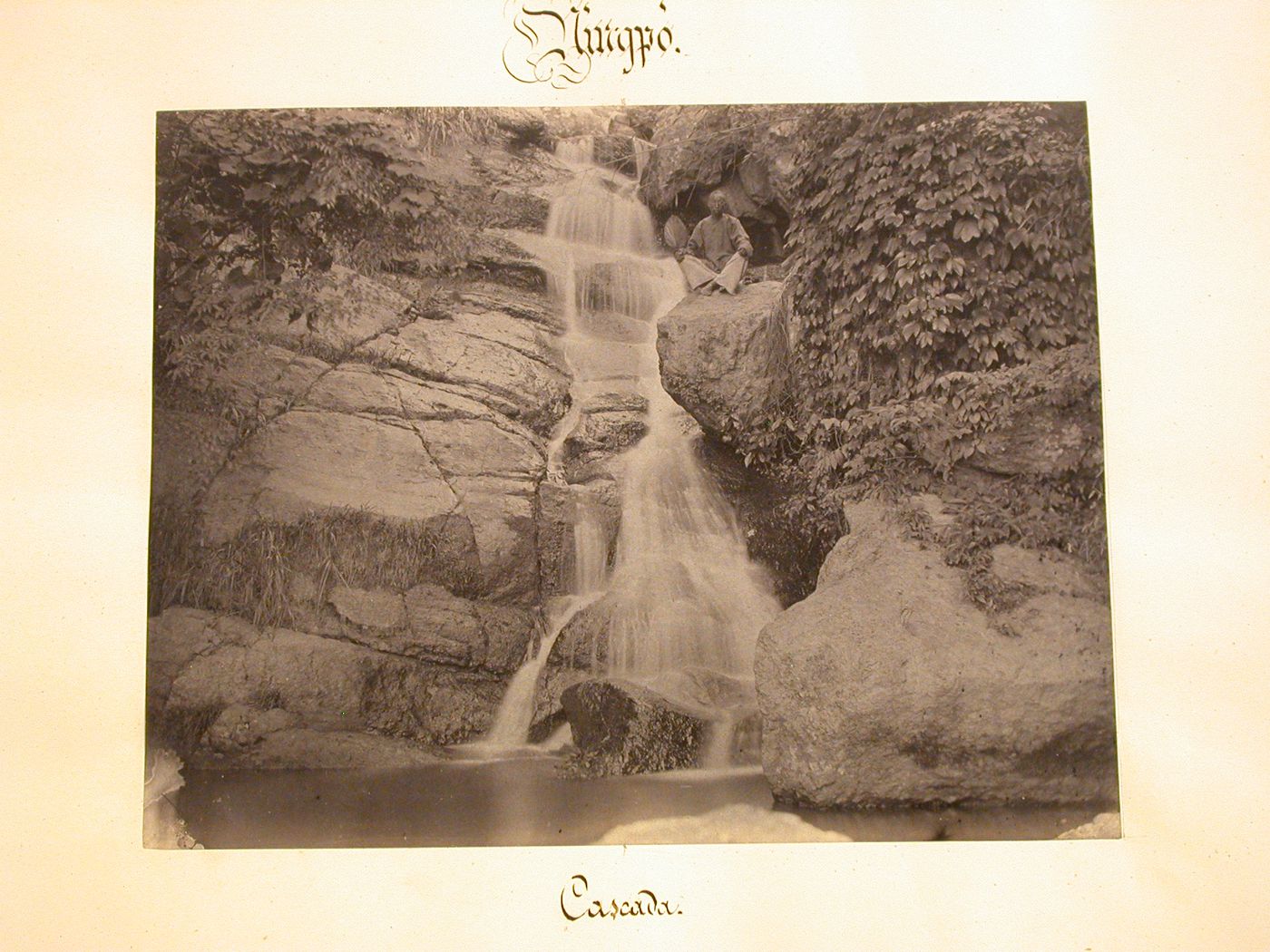 View of a man sitting cross-legged beside a waterfall in the vicinity of Ningpo (now Ningbo Shi), Cheh-kiang Province (now Zhejiang Sheng), China