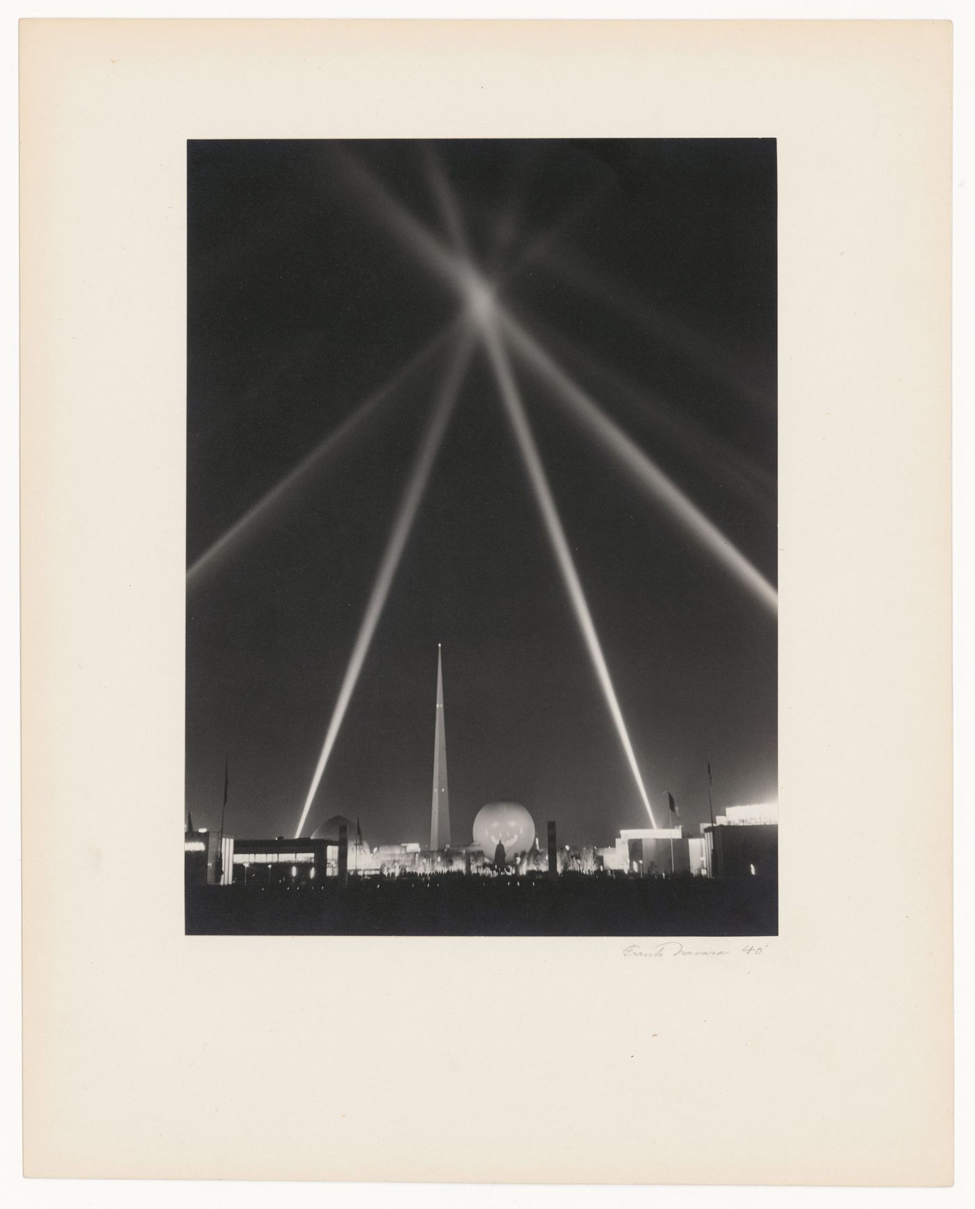 New York World's Fair (1939-1940): Night view of Fair with Statue of George Washington, Trylon and Perisphere lit for night, and light beams in a star pattern in sky