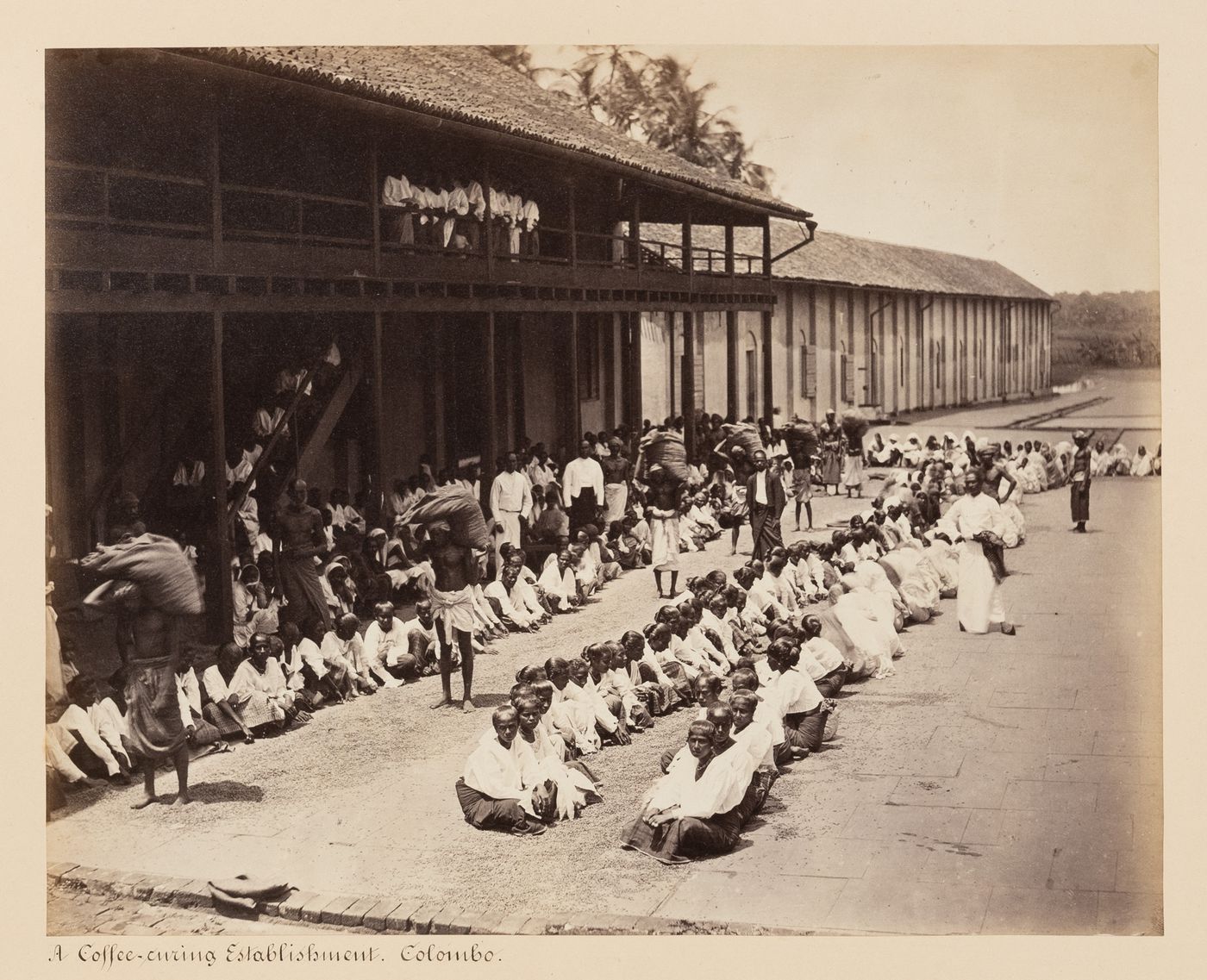 View of workers sitting in front of a building, Colombo, Ceylon (Sri Lanka)
