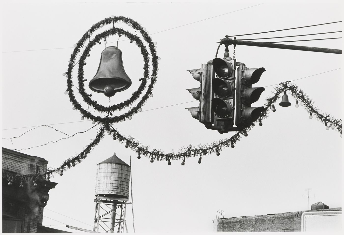 View of street decorations, including a bell, wreath, lights and garland, showing traffic signals with a water tower in the background, Hoboken, United States