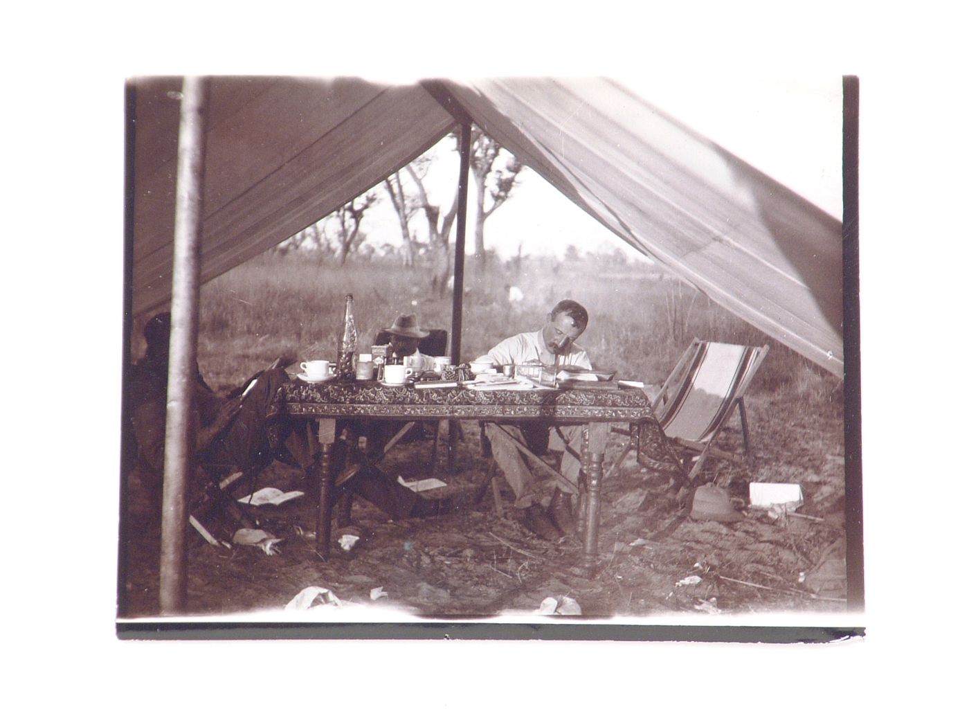 View of three men involved in the Zambezi bridge project, sitting around table in tent, near Zambezi River