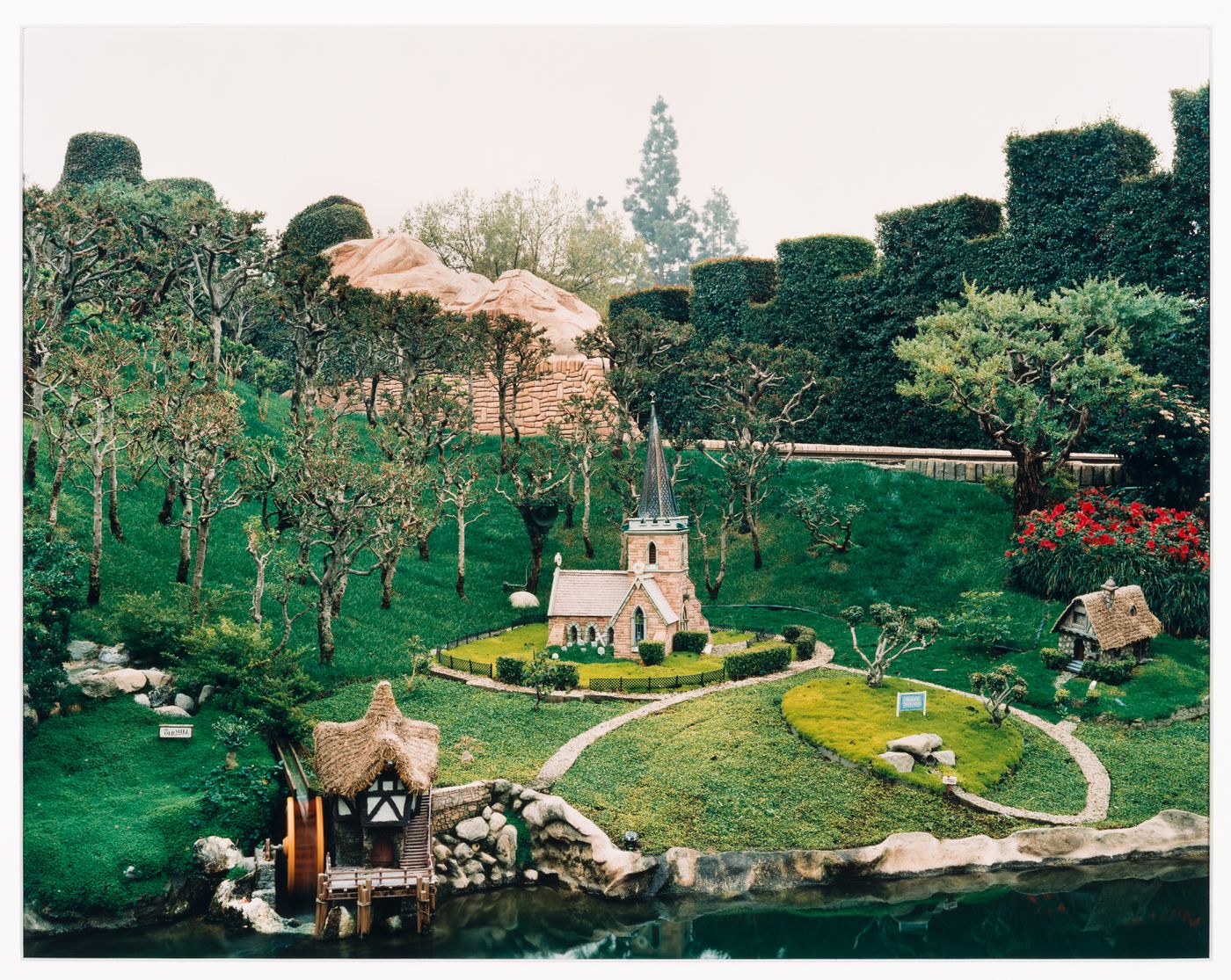 View of Storybook Land showing miniature church, house and old mill on artificial stretch of water, Disneyland, Anaheim, California