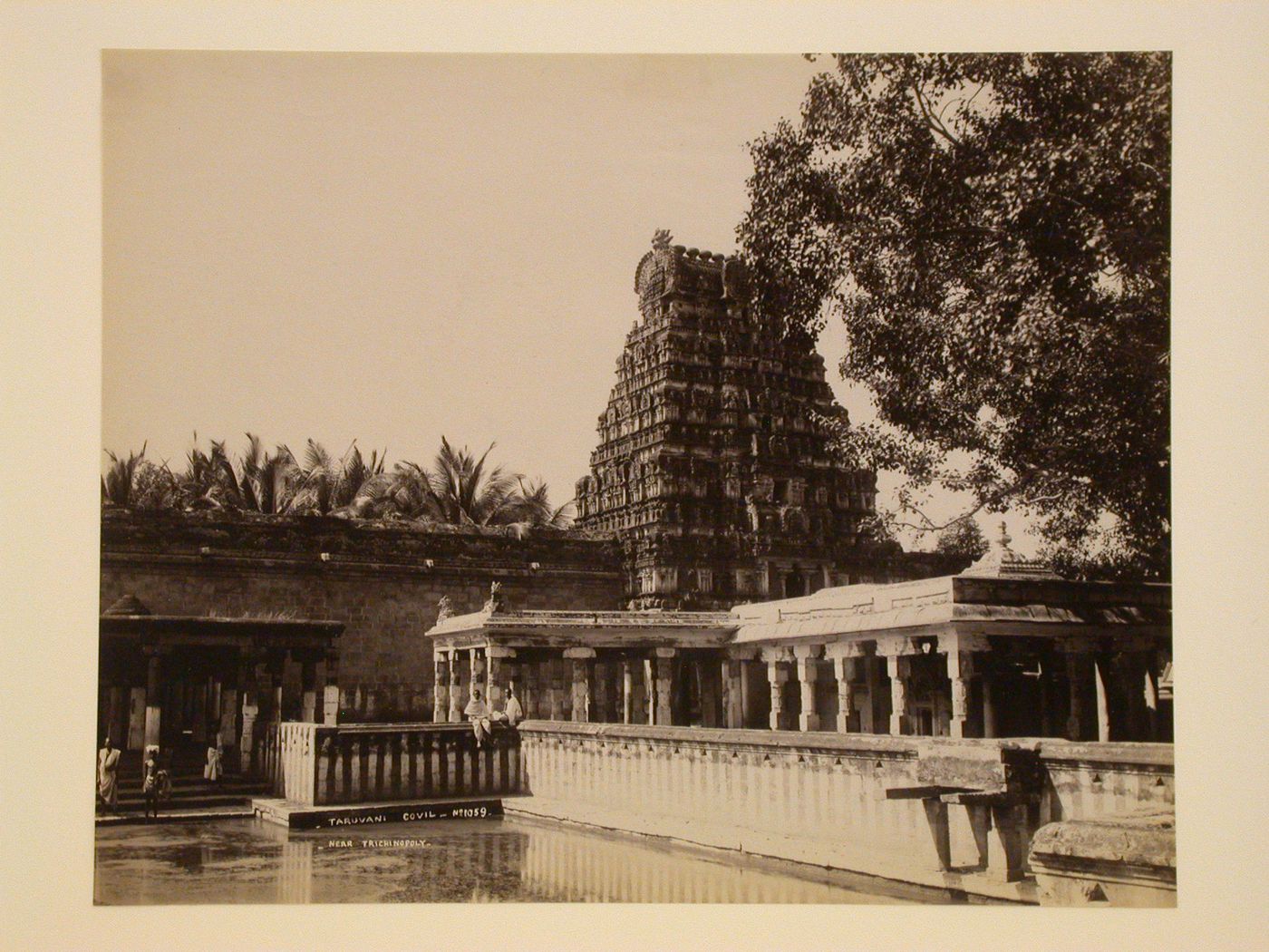 View of a water tank and ghat showing Tiruvanaikkovil (also known as Tituvanaikka and Jambukeswaram) in the background, Tiruvanaikka village, near Seringham (now Srirangam), India