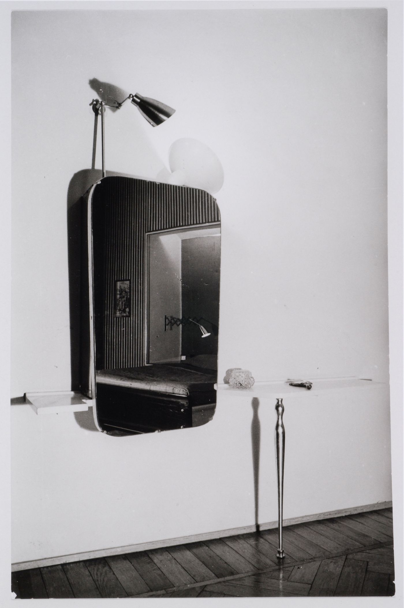 IInterior view of the bedroom of Casa Ada and Cesare Minola showing a shelve embedded in the wall, a revolving mirror and a lamp with a double metal reflector on top supported by brass arms with mechanical joints patented by Carlo Mollino, Turin, Italy