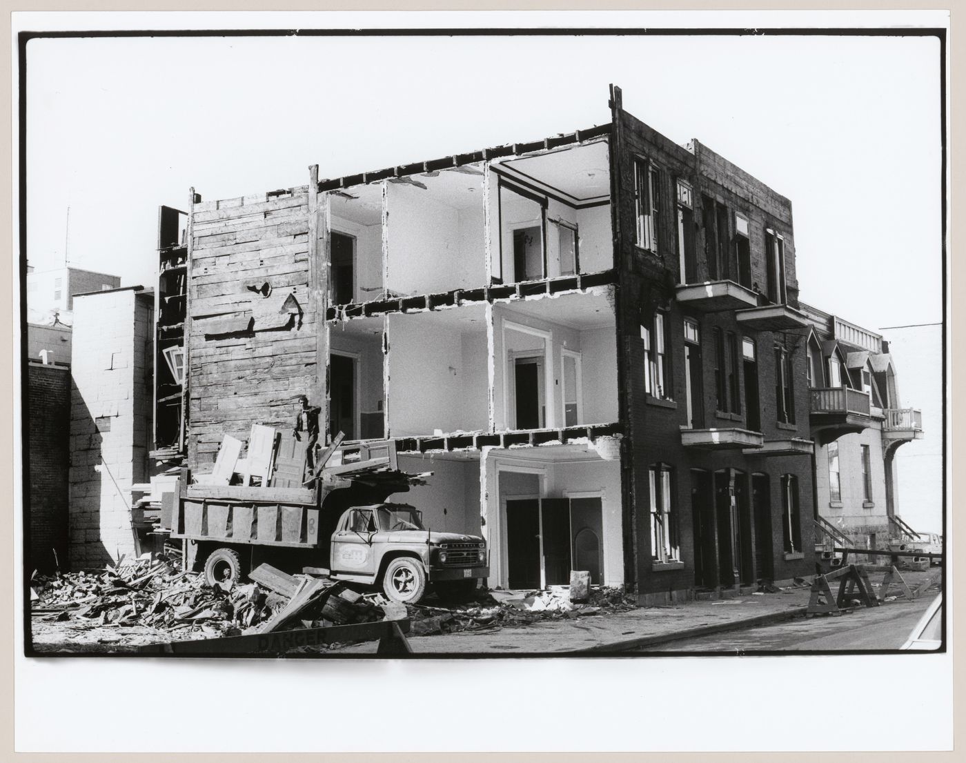 View of the principal and lateral façades of an apartment house under demolition showing the interior of the building, rue  Notre-Dame, Montréal, Québec, Canada
