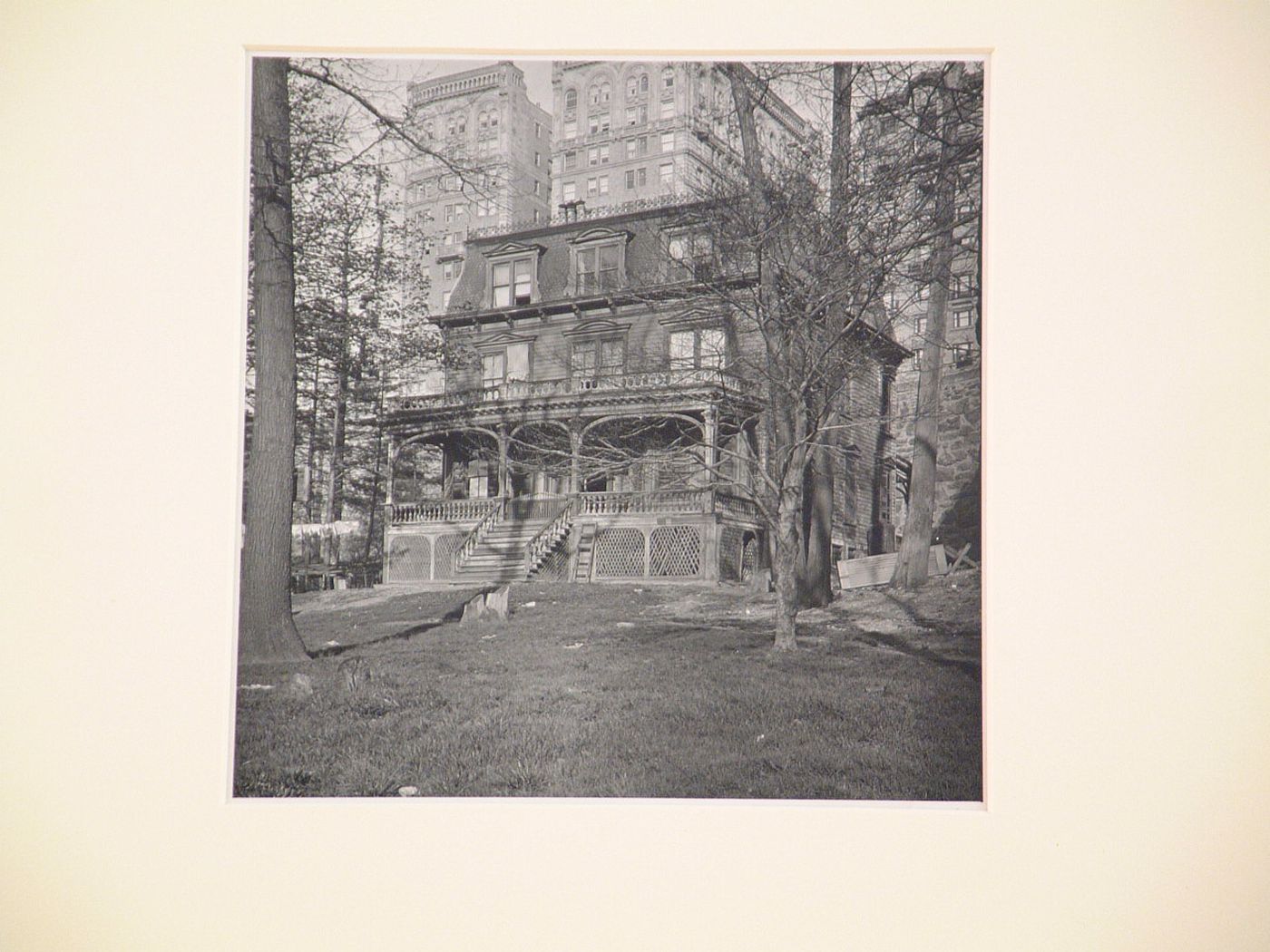 Wooden house with trees surrounding, Stone wall and tall stone buildings behind, New York City, New York